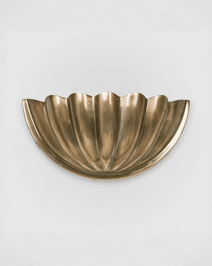 Brass shell-shaped wall sconce light gray background