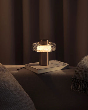 Hand cast glass portable table light in a bronze finish placed on a book 