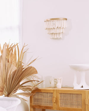 Cascading ceramic bead wall light hanging above light coloured rattan console