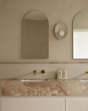 Scalloped wall sconce styled in a minimalist bathroom