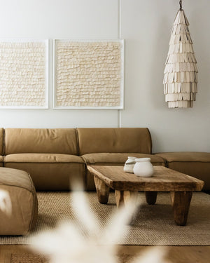 White ceramic pendant light hanging in a modern living room above a brown couch.