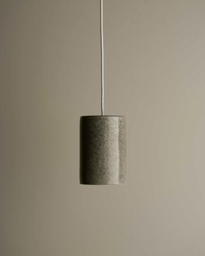 Minimalist pendant light with a cylindrical shade on a plain background