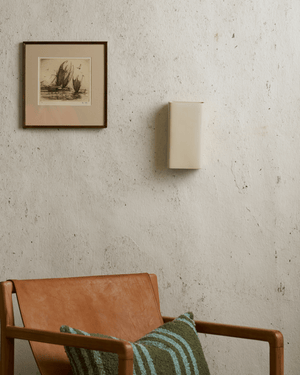 rectangular wall light on a textured cream wall with framed painting and chair.