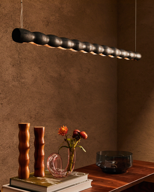 Modern pendant light fixture hanging above a wooden surface with decorative items.