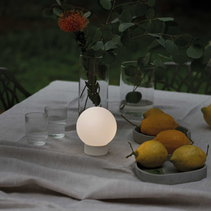 Mini Spherical Portable Glass Lamp on a table outside next to glass and lemons