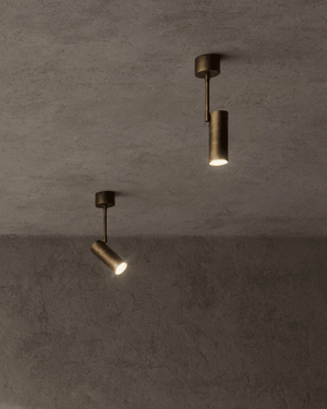 Two aged brass spotlights on a textured grey wall