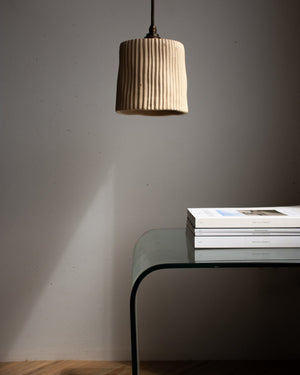 Beige pendant light hanging above a glass table with books