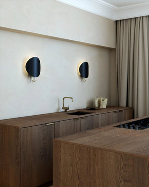 Two Black Modern Curved Disc Wall Lights in wooden kitchen interior space. 