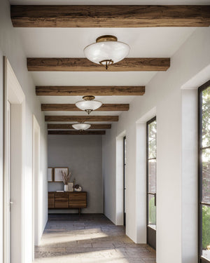 three large ceiling light made from glass and brass displayed in the corridor of a farmhouse style house