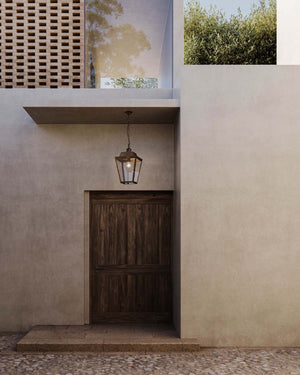 Pre-aged brass lantern pendant hanging over a wooden door entrance of a modern house