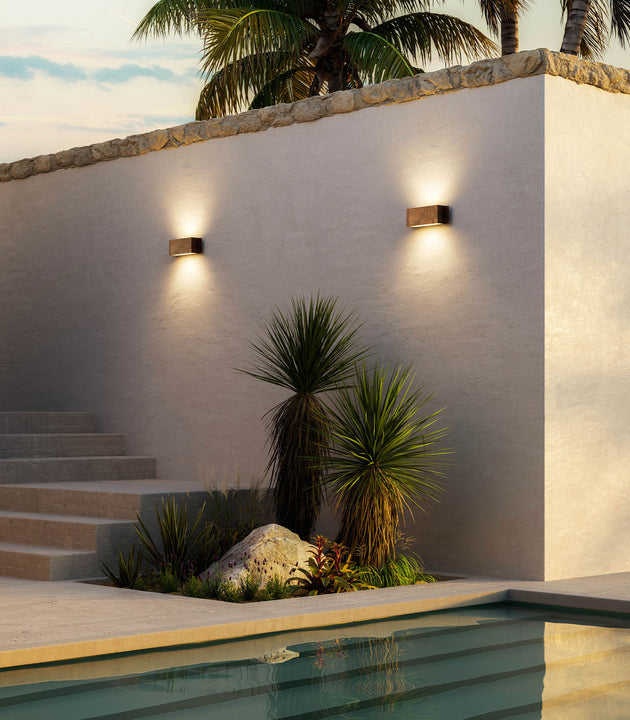 Outdoor setting with a pool, steps, and italian made wall-mounted lights against a white wall.