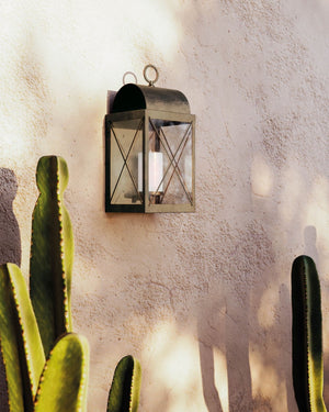 Aged brass lantern wall light displayed in a hacienda exterior near cactuses