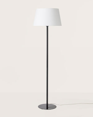 Floor lamp with a white shade and black base on a light gray background