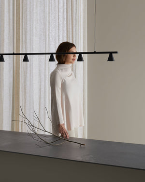 Woman standing with a minimalistic conical black pendant light 