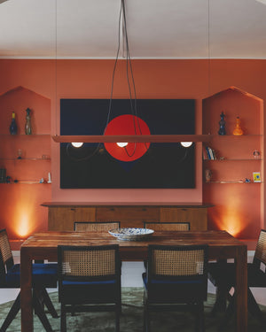 Modern kitchen with orange walls, wooden dining table, and pendant light.