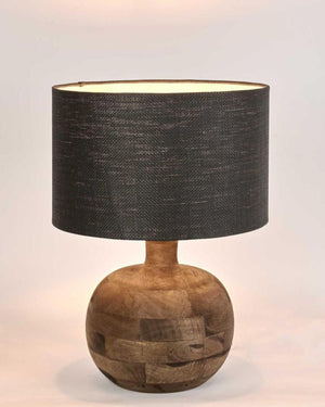 Table lamp with round wooden base and black fabric shade on a light background