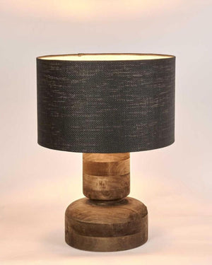 Table lamp with wooden base and black fabric shade on a light background