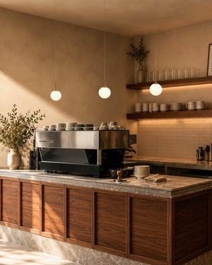 A modern cafe setting with wooden cabinets, hanging sphere pendant lights and shelves in the background.