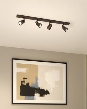 Minimalist four spotlight bronze bar fixture on white ceiling above abstract painting