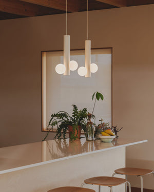 Modern kitchen with pendant lights, plants, and a window on a beige wall.