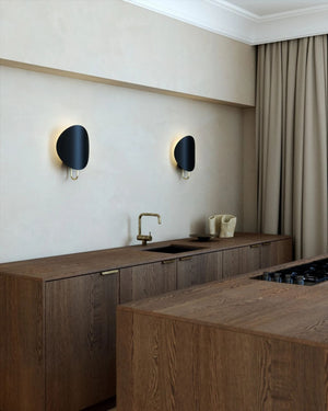 Two Black Modern Curved Disc Wall Lights in wooden kitchen interior space. 