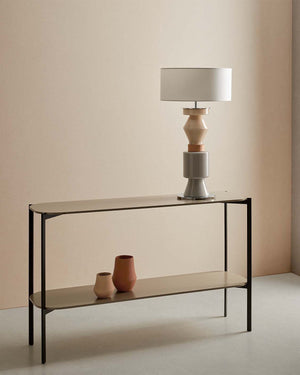 Console table with a lamp and vases against a beige wall
