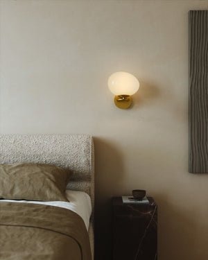 Warm Styled Bedroom with a wall-mounted orb wall lamp and textured headboard. 