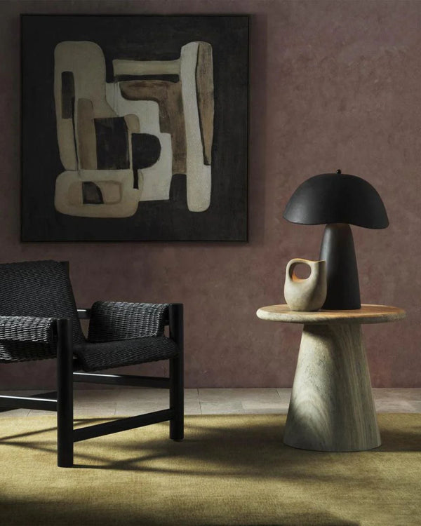 Organic Fibreglass Table Lamp in black on stone side table beside woven lounge chair in moody living room