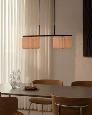 Pleated Fabric Linear Pendant Light with two shades hanging above dining table with wooden chairs in neutral interior