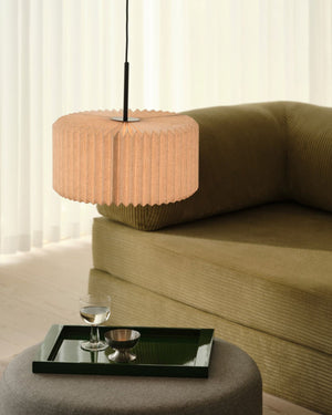 Pleated Fabric Pendant Light hanging above coffee table in living room with olive sofa and warm ambient glow