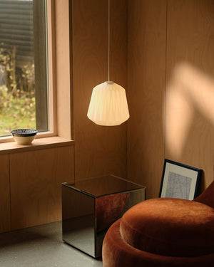 Pleated opal glass pendant above side table illuminated