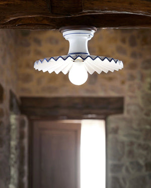 Ceiling light fixture with decorative ceramic shade in a stone-walled room
