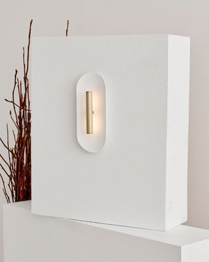 Reflector wall sconce light in a brushed brass finish mounted on textured wall