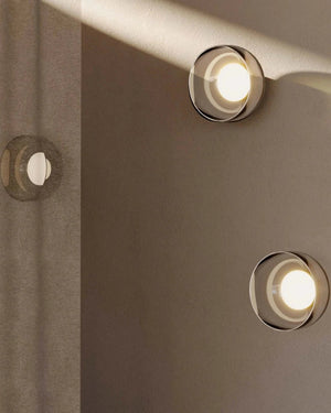 Close-up of three round glass lights on a textured wall.