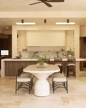 A modern dining area and spacious kitchen with beige walls, wood cabinetry, and rustic downlights