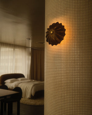 Hexacorallia brass wall sconce hanging on tiled column in a bedroom with light on