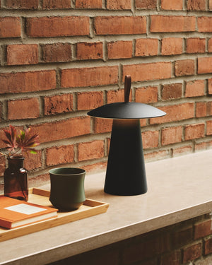 Black lamp on a stone surface with a brick wall background - Lighting Collective 