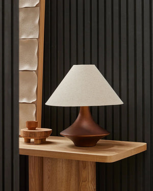Sculpted bronze table lamp on oak console with textured stone artwork in dark contemporary interior