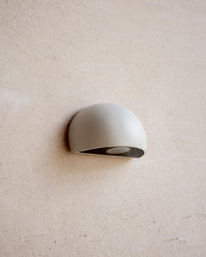 A semicircular indirect step light mounted on a textured white wall
