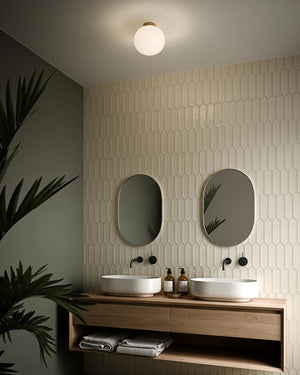 Simple Scandinavian Ceiling Light in a Bathroom with two sinks, mirrors, and decorative elements on a tiled wall - Lighting Collective 