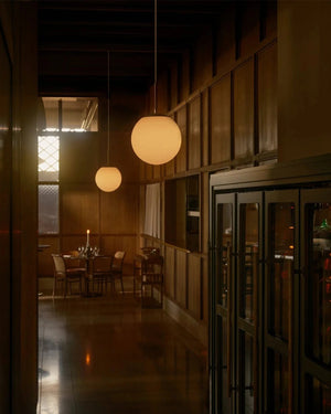 Simplistic Opal Sphere Pendant in warm Interior Setting with table in the distance - Lighting Collective 
