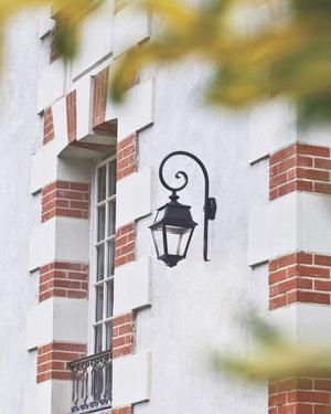 Black swan neck wall light mounted beside a window on a brick and stone facade