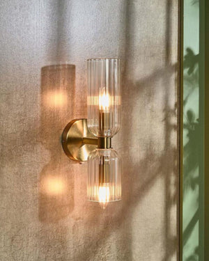 Glass wall light installed on textured stone wall beside window for ambient lighting