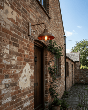 Vintage-style light fixture with a copper finish mounted on an outdoor brick wall