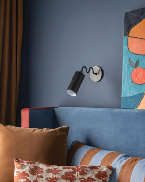 Old bronze wavy arm wall light mounted bedside on blue wall in contemporary bedroom
