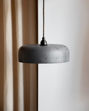 Concrete pendant light hanging against a neutral background