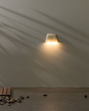 Wall-mounted light fixture casting a warm glow on a plain wall.