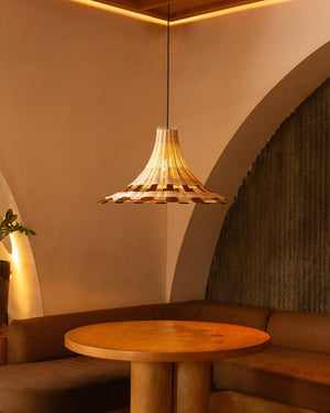 A bohemian style woven teak rattan pendant lighting suspended above wooden round table in warm interior restaurant
