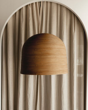 Rattan pendant light hanging against a beige curtain