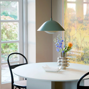 double domed matt metal pendant light with dusty green finish in a dining room with a view on a garden